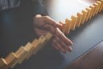 Problem Solving Close Up of Hand Preventing Dominos from Falling